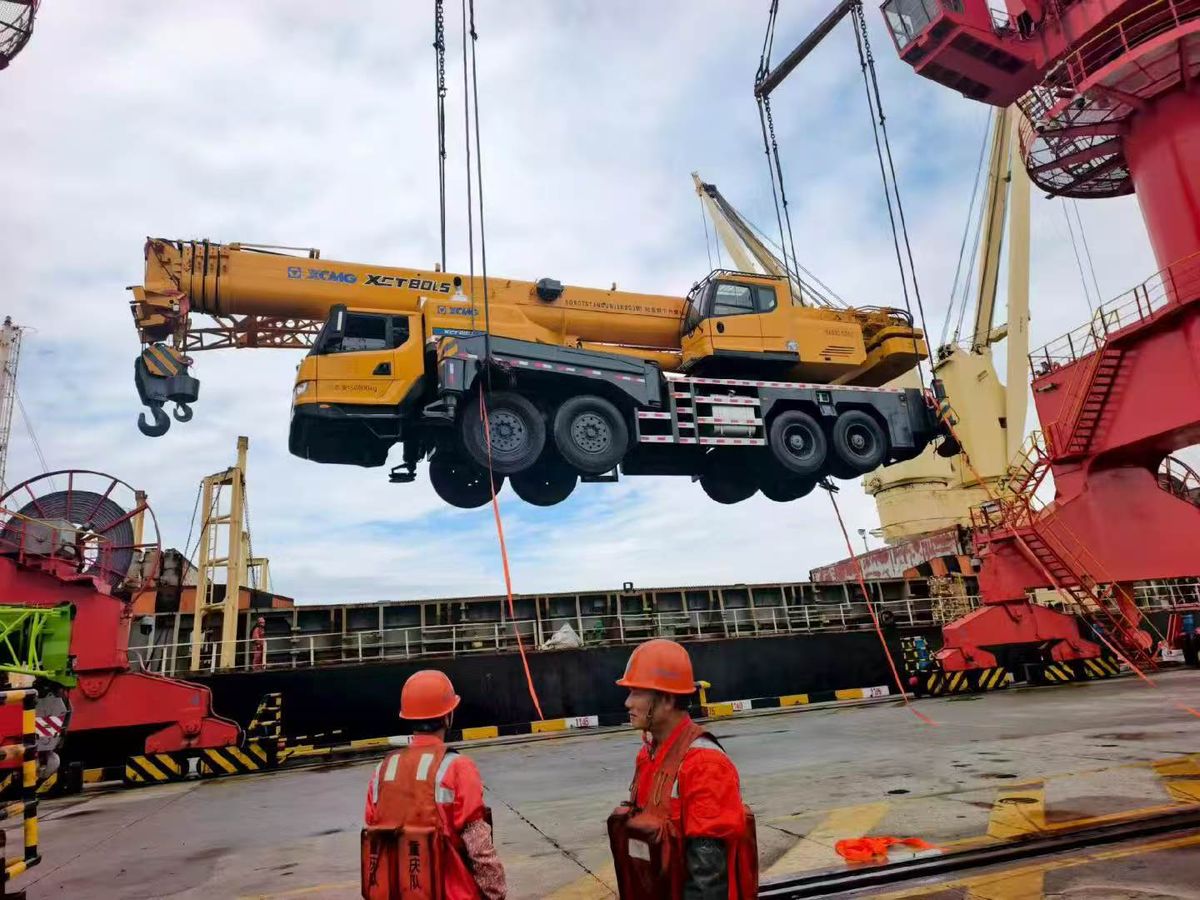 A mobile crane being lifted during vessel loading at a port